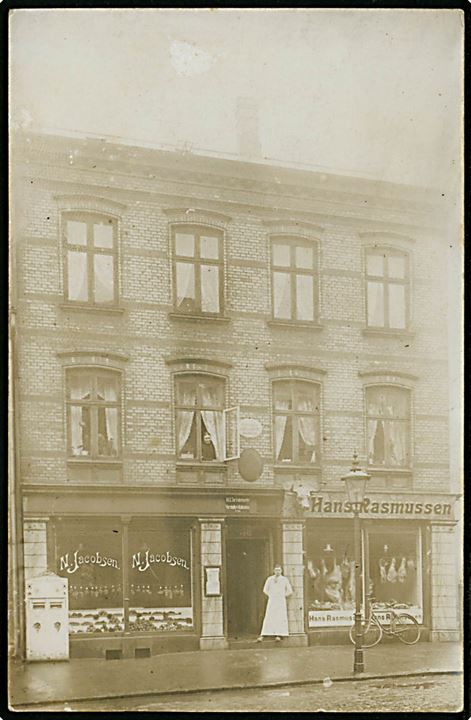 Odense, Nørregade 40 med N. Jacobsen frugt- og grønt, Slagter Hans Rasmussen og lotterikollektion. Fotokort u/no. dateret d. 23.12.1910.