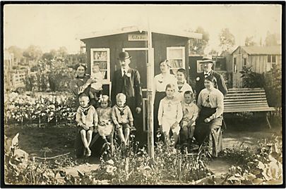 Købh., familie forsamlet i kolonihave med Asla-huset. Fotokort u/no.