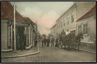 Hobro. Hjørnet af Skibsgade og Adelgade med posthus (Opført 1914) og postvogn, samt N.P. Rasmussens (som står i døren) Kolonial og Urtekramforretning. C. Qvist & Co. u/no. 