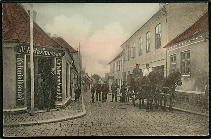 Hobro. Hjørnet af Skibsgade og Adelgade med posthus (Opført 1914) og postvogn, samt N.P. Rasmussens (som står i døren) Kolonial og Urtekramforretning. C. Qvist & Co. u/no. 